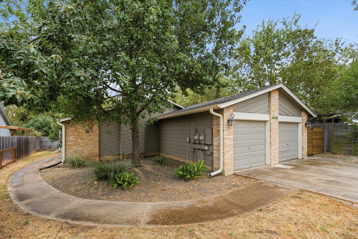 Mature trees shade the concrete driveway and walk