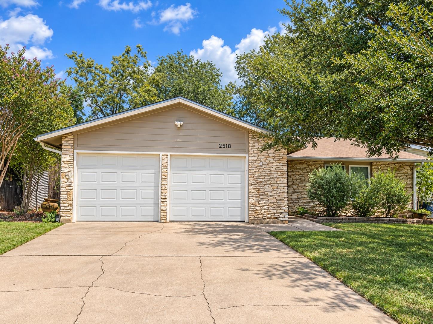 Textured stone accents and a wide driveway define
