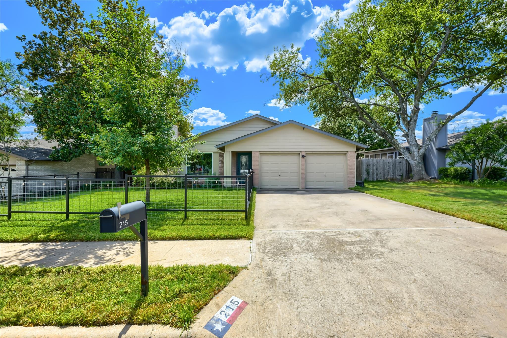 Mature trees shade a wide concrete driveway leadi