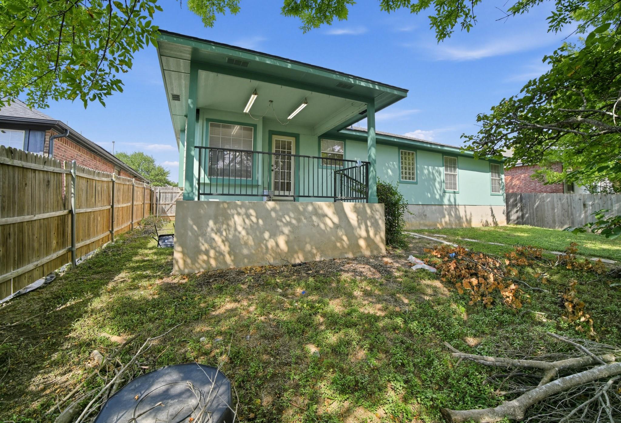 A spacious backyard features a covered concrete p