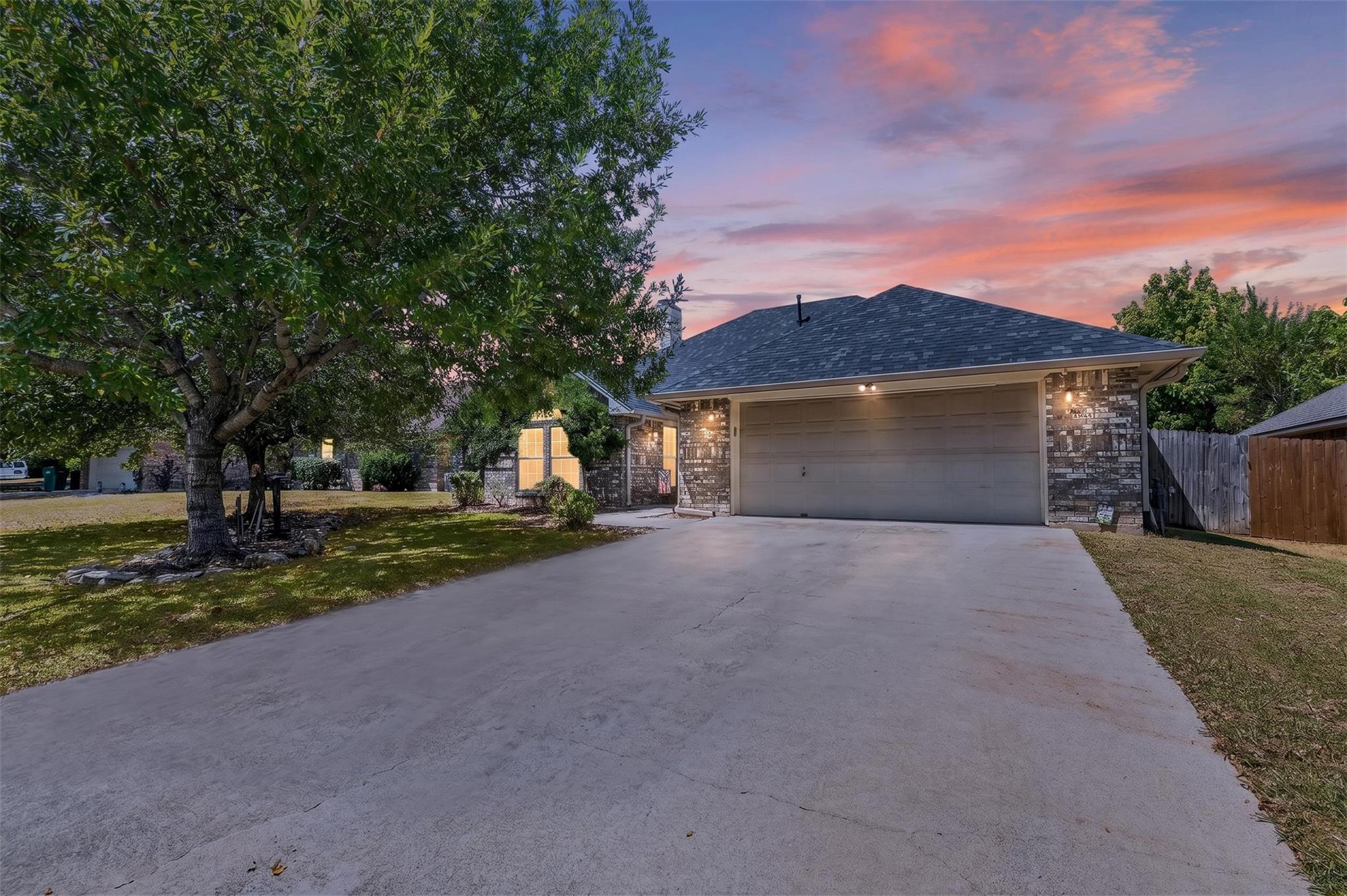 Mature trees frame a wide concrete driveway leadi