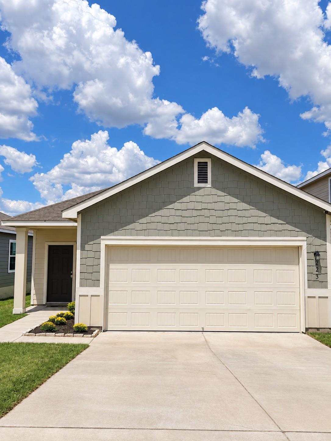 Shingle siding and a neat concrete driveway estab