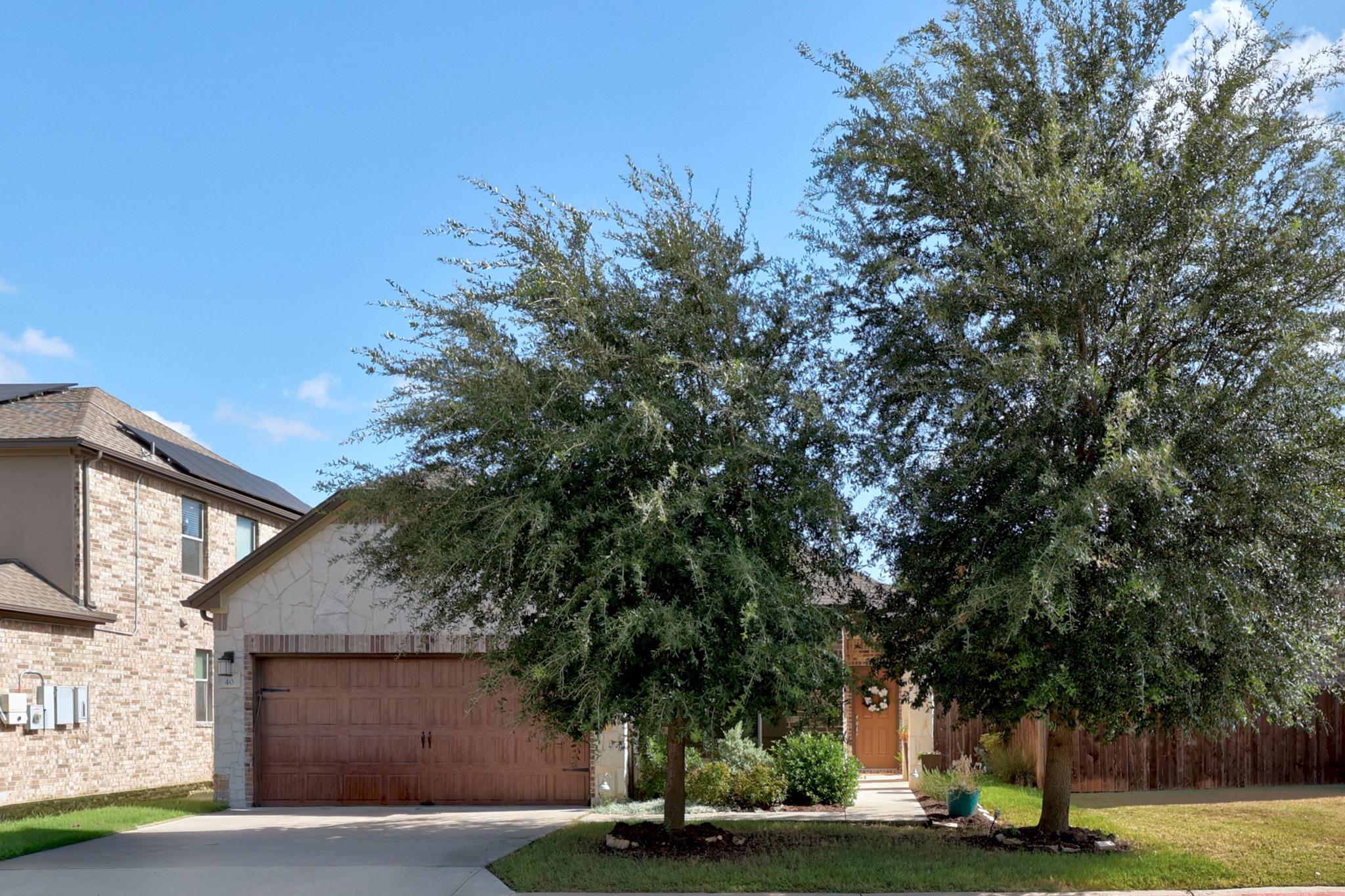 Mature shade trees and stone accents framing the 