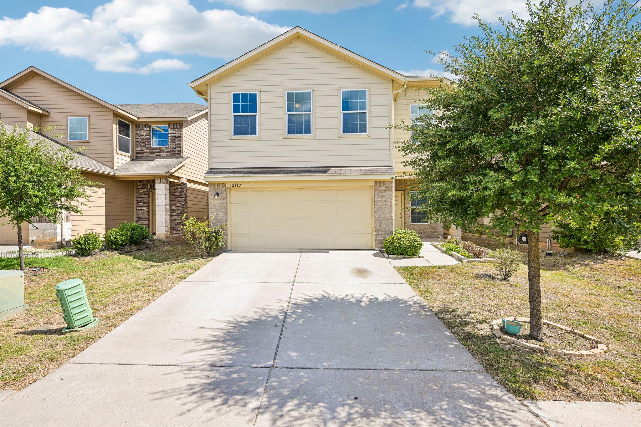 A wide concrete driveway leads to a two-story hom