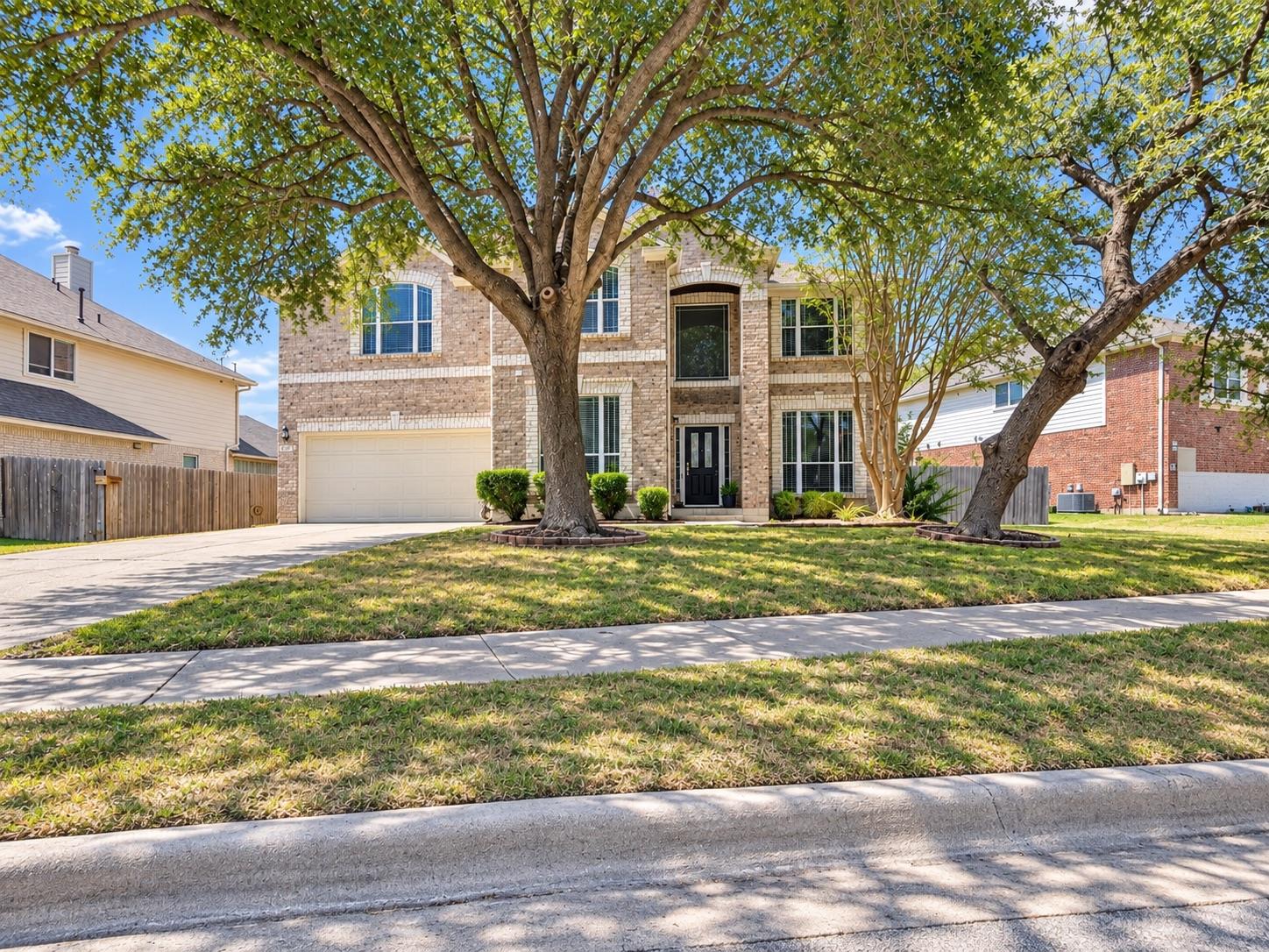 Mature trees shade a classic brick facade with a 