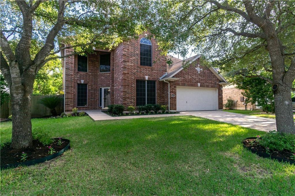 Mature shade trees frame a classic brick facade w