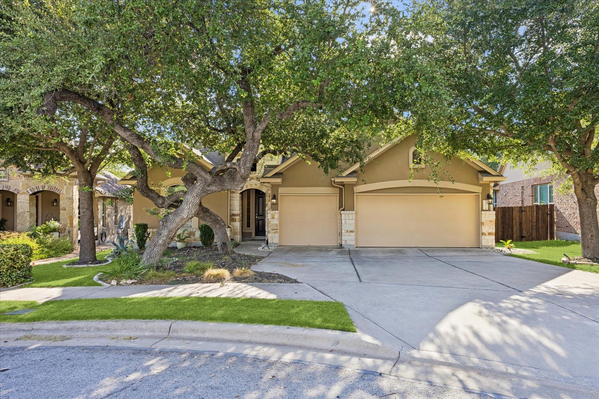 Mature shade trees frame a classic stone and stuc
