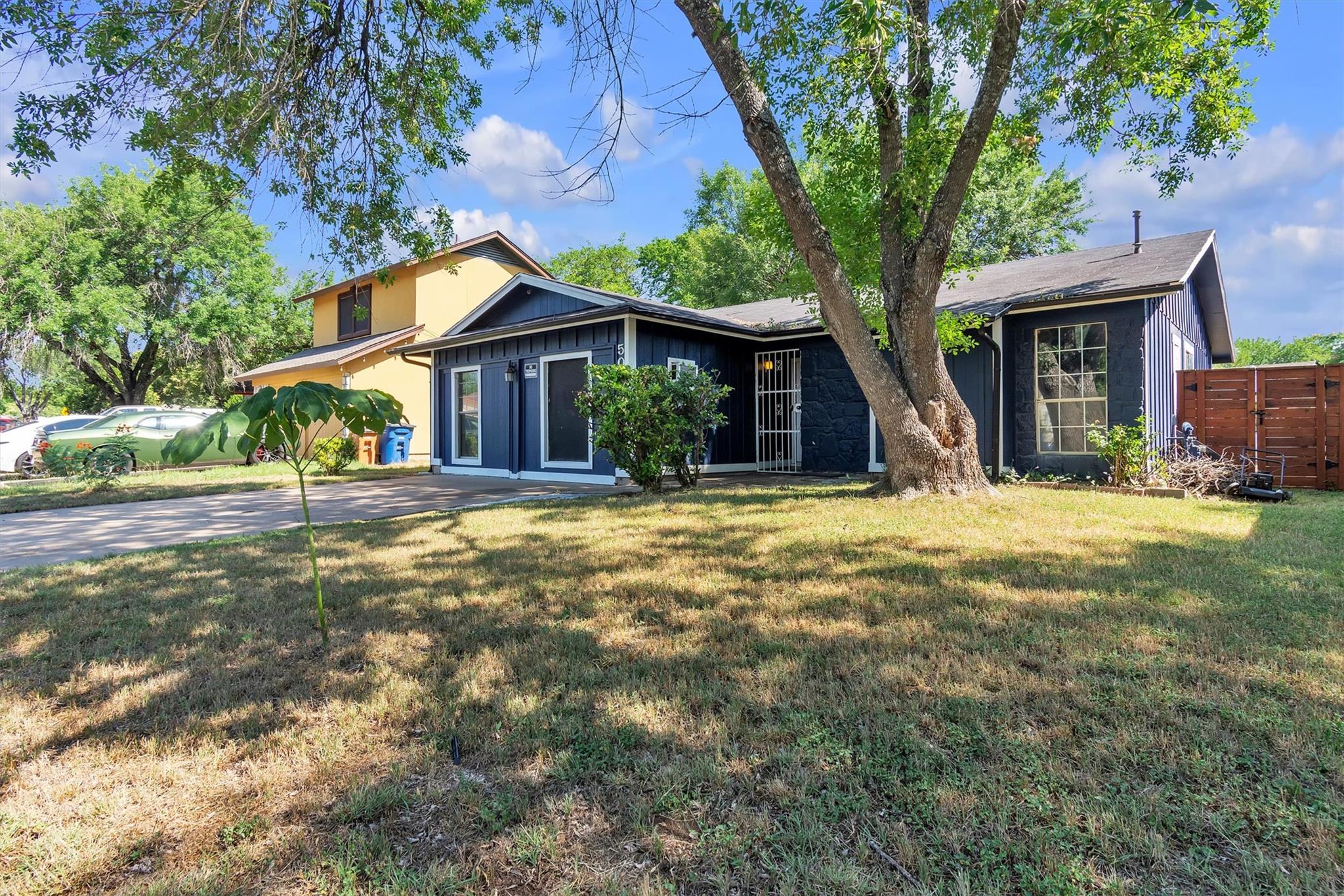 Mature trees shade the grassy front yard of this 