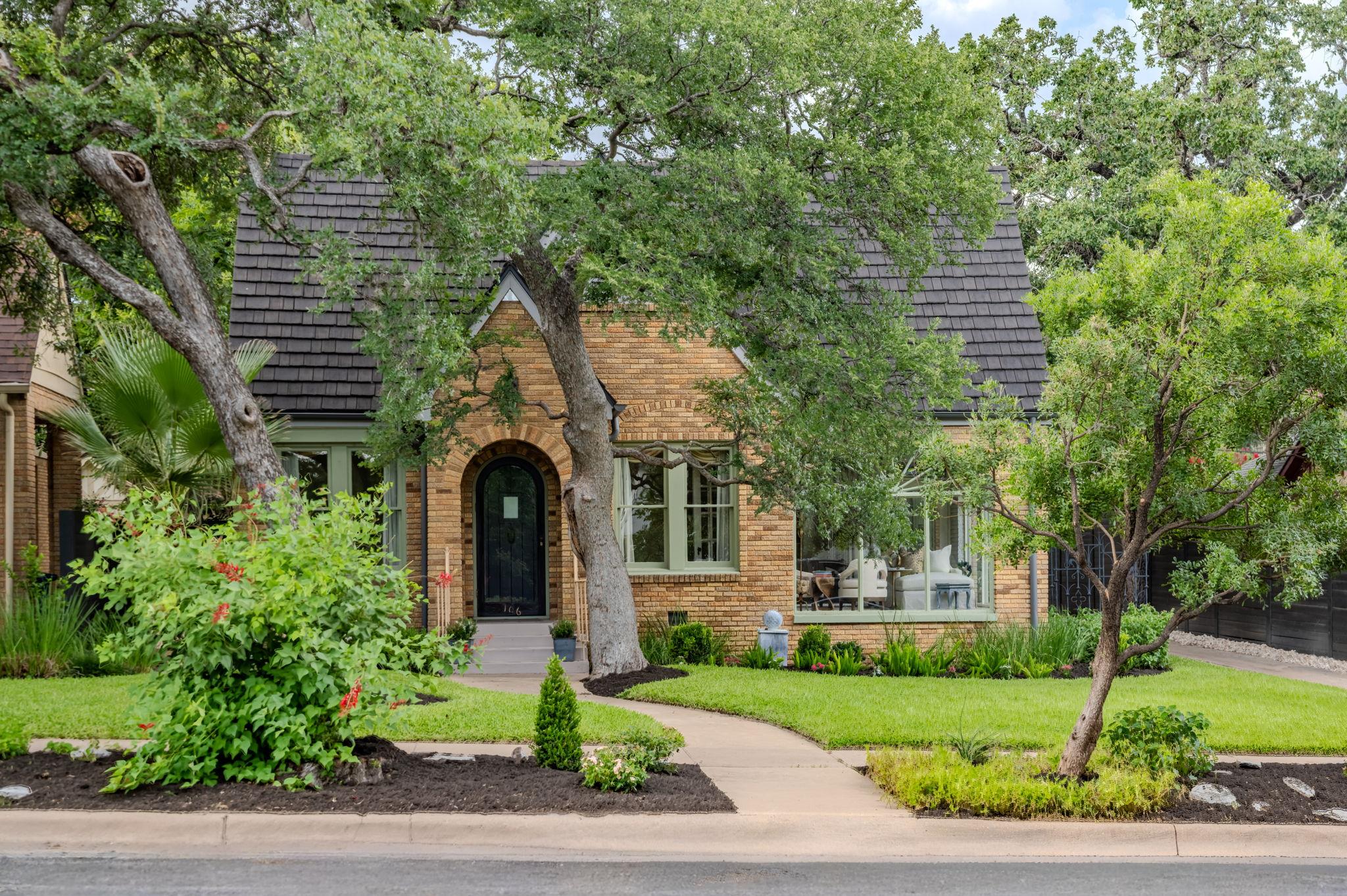 Mature trees shade a classic brick exterior featu
