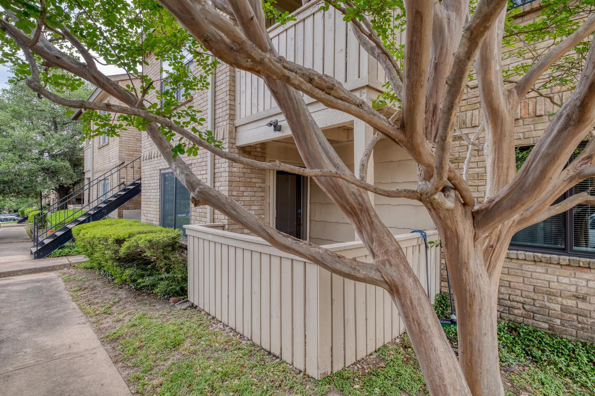 Mature trees shade a private ground-level patio a
