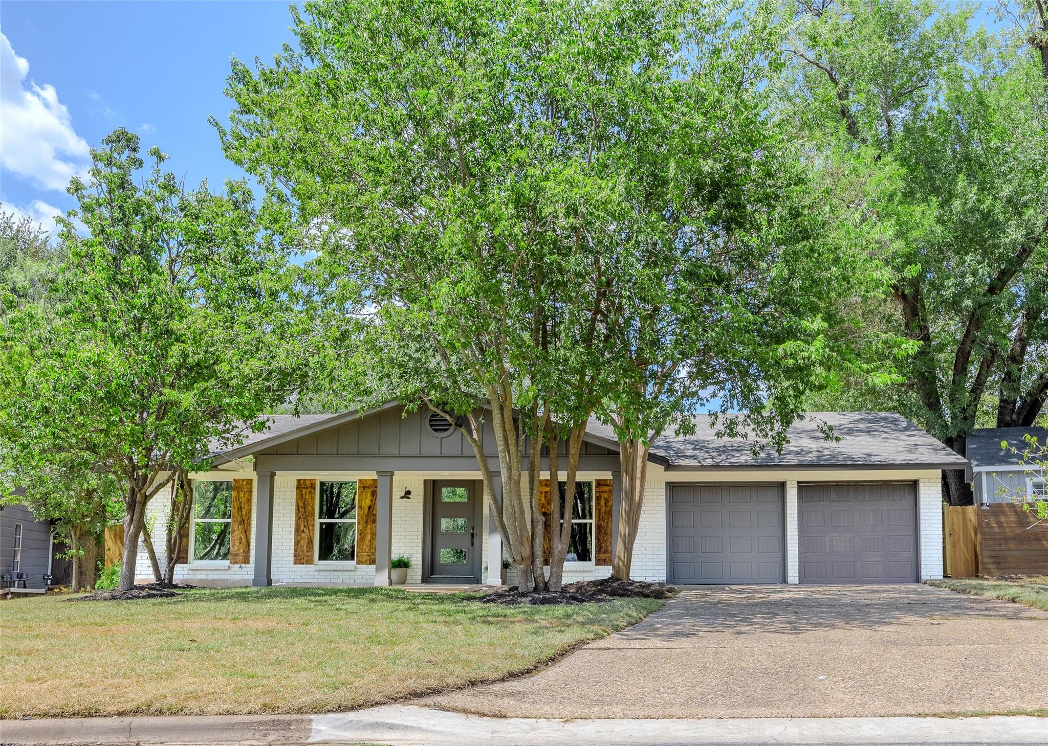 Mature trees shade the brick and siding exterior 