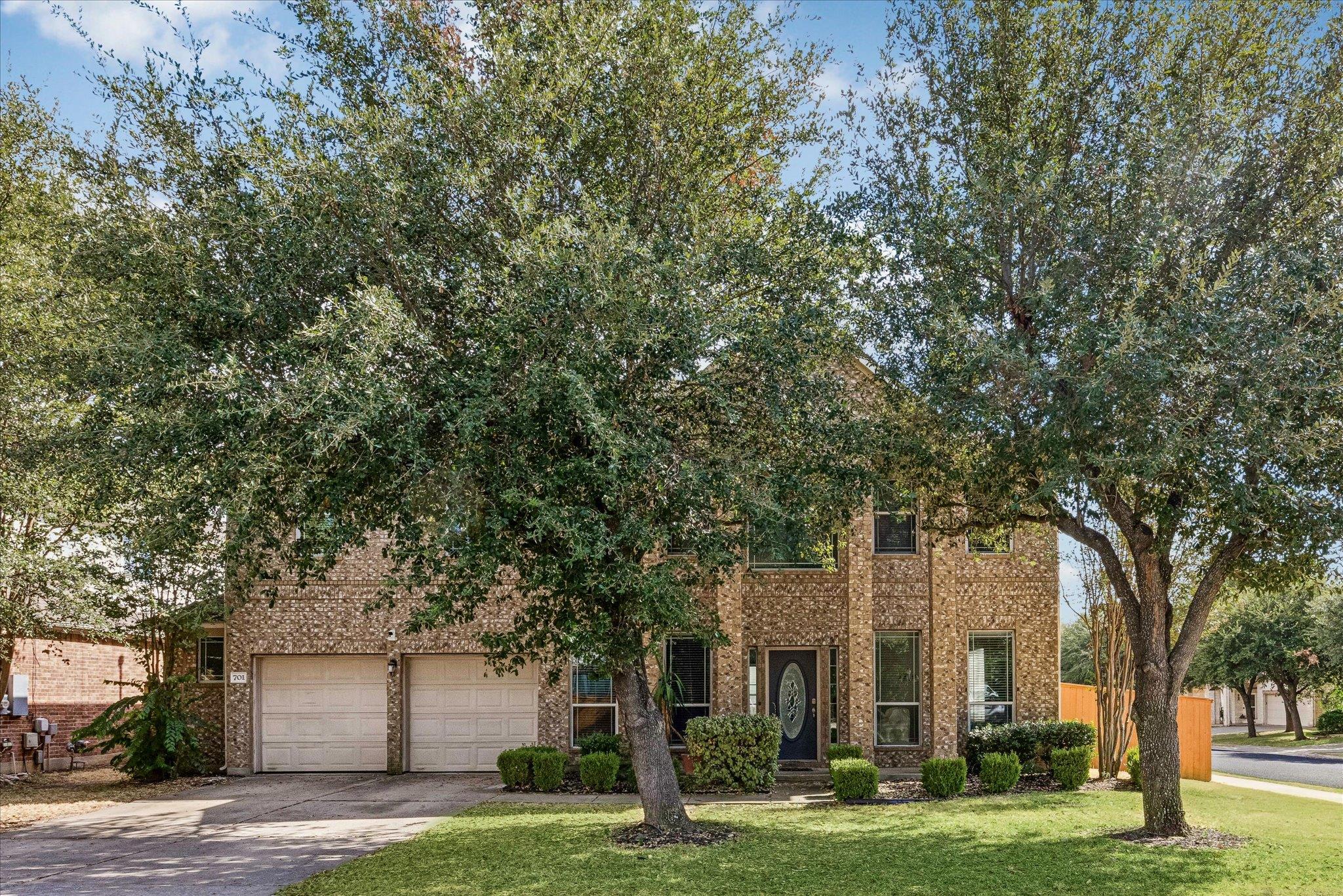 Mature trees frame a classic brick facade with a 