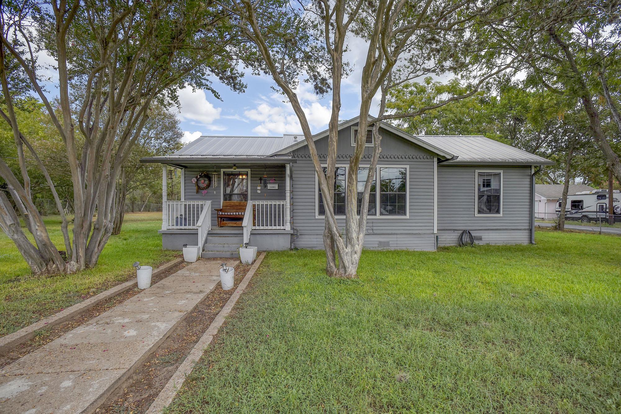 Mature trees shade the front lawn and walkway lea