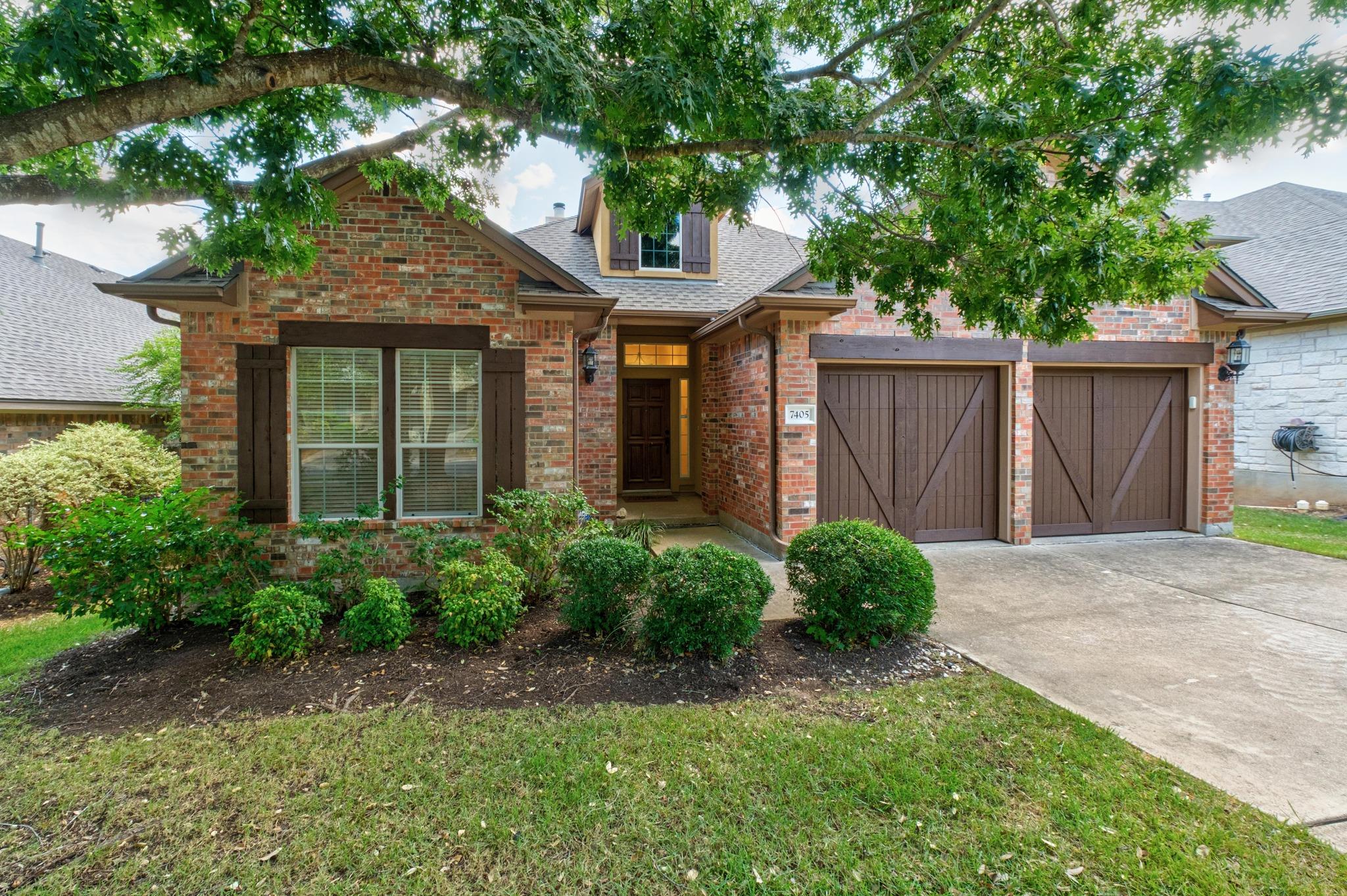 Mature trees frame a classic brick exterior compl