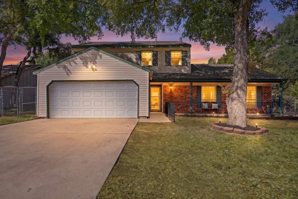 Mature trees shade a classic brick and siding ext