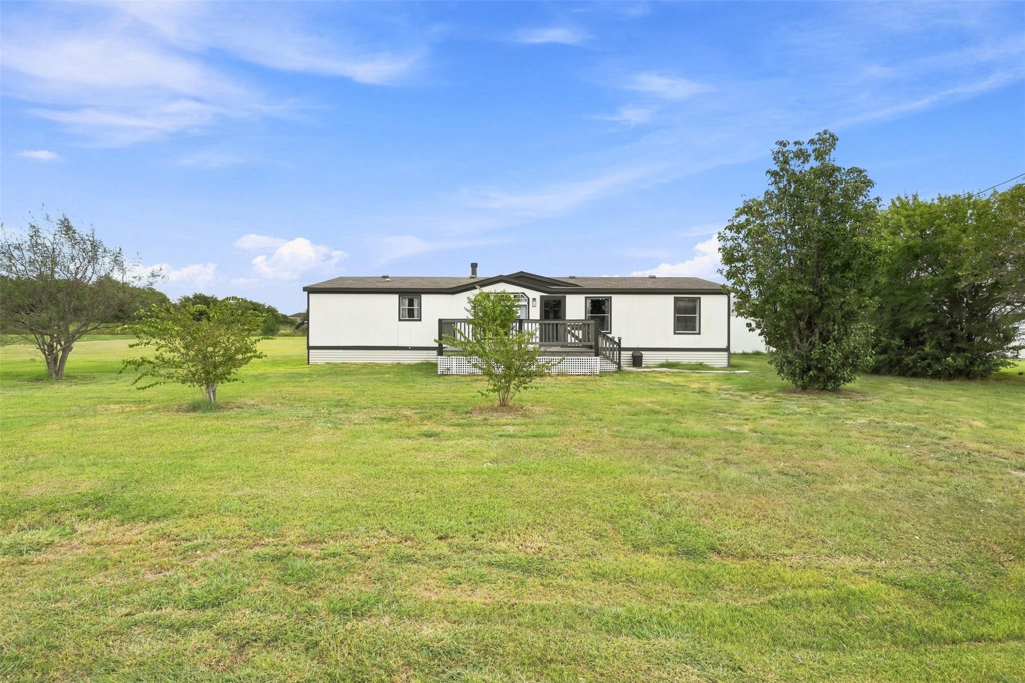 Mature trees frame the wide yard surrounding this