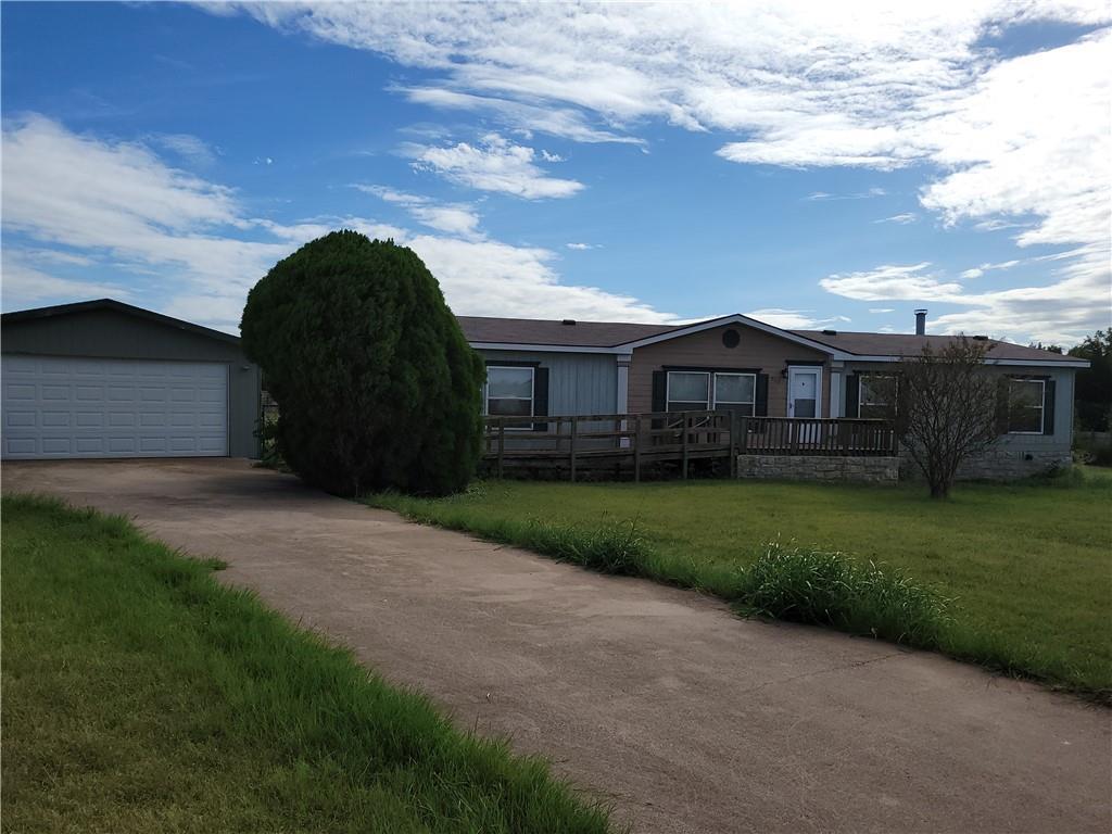 A long paved driveway leads toward the detached g