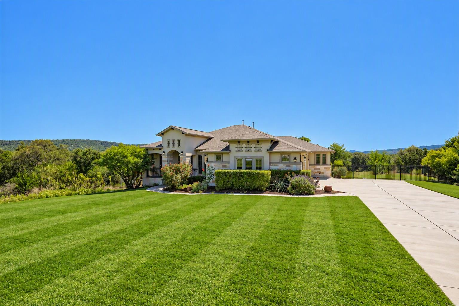 An manicured green lawn leads to a stone and stuc