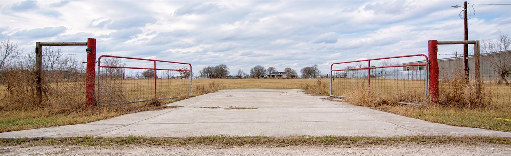 A secured entrance gate opens to a vast, level pa