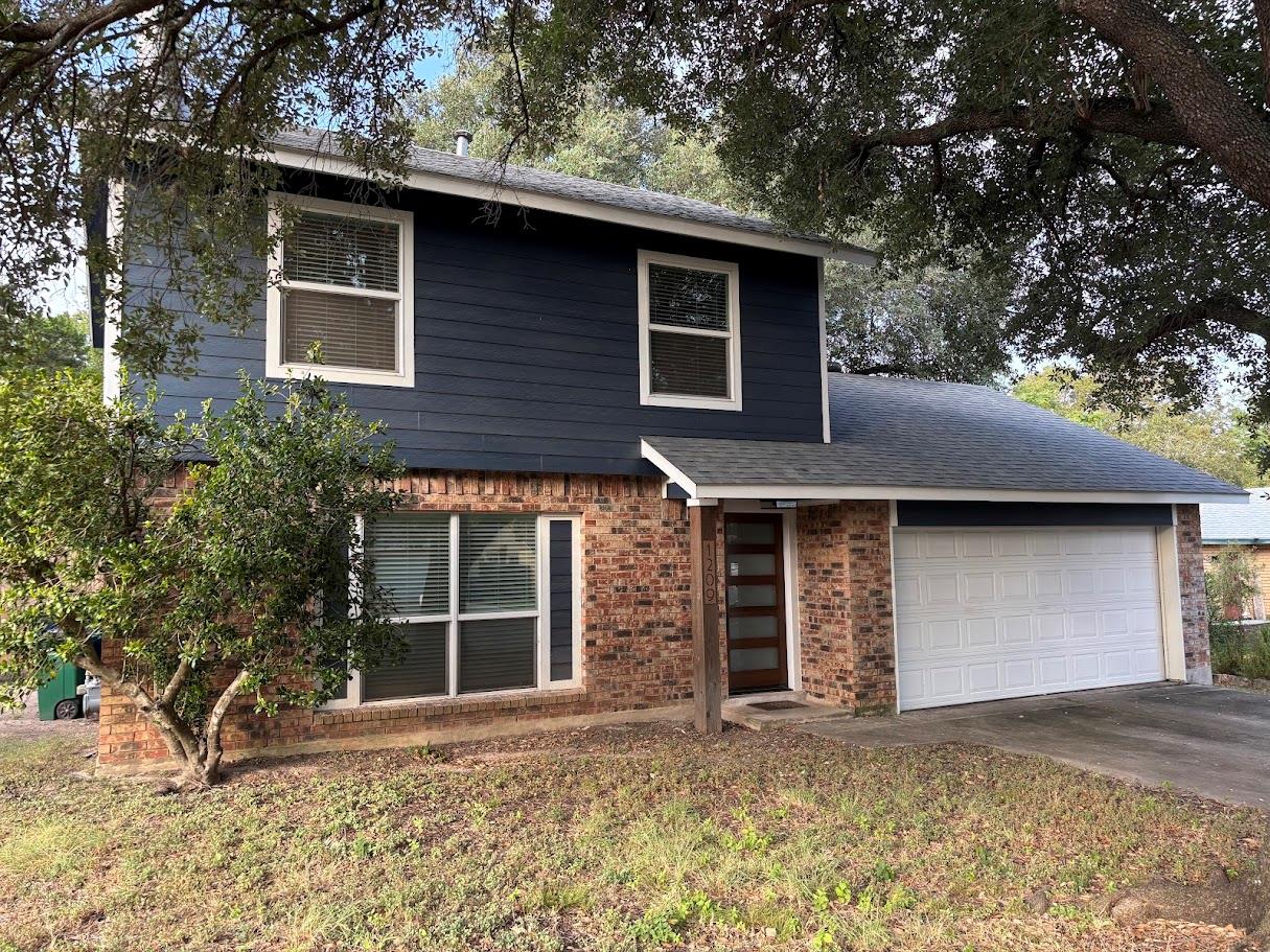 Mature trees shade a two-story exterior blending 