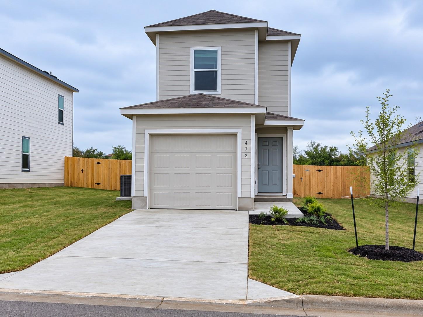 A concrete driveway leads toward the single-car g