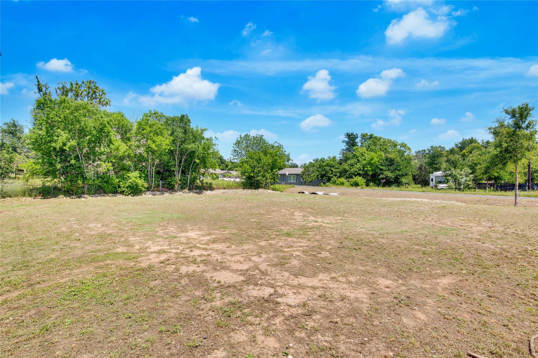 Mature trees frame a spacious open lot under clea