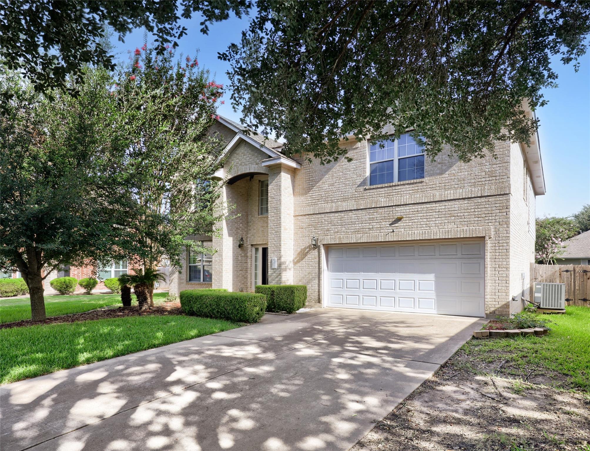 Mature trees shade the driveway of this two-story