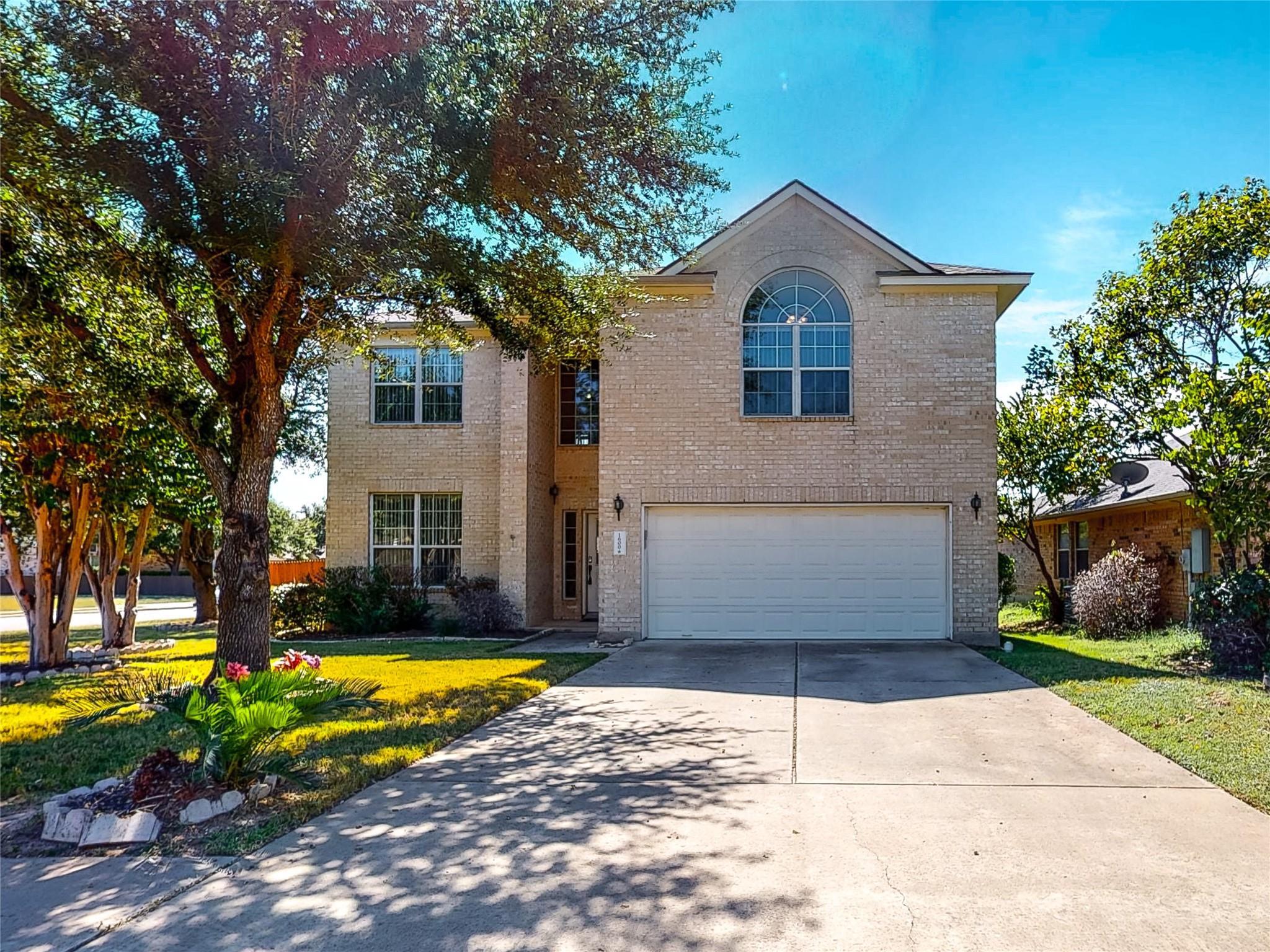 Mature trees frame the classic brick exterior and