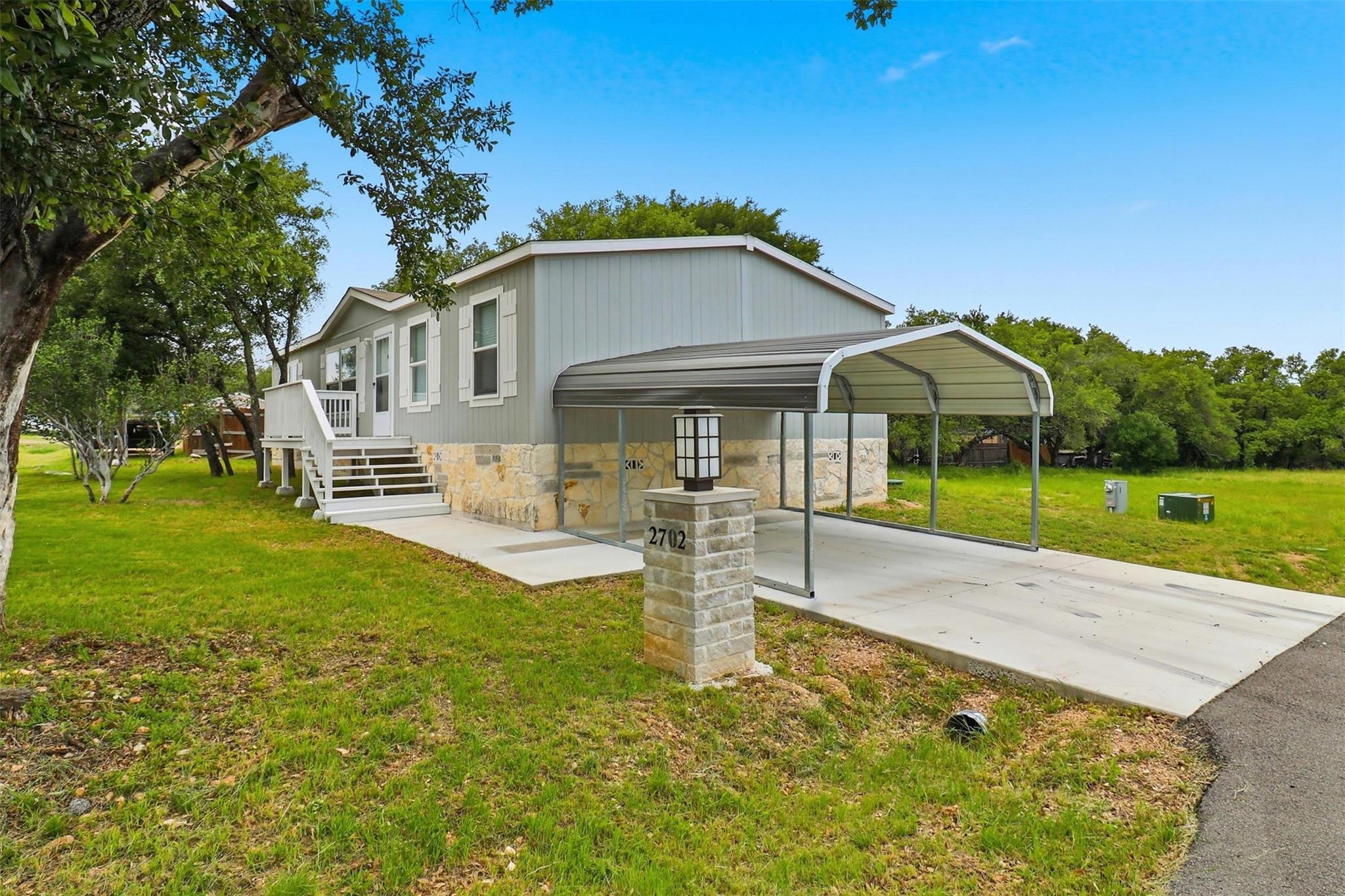 Mature trees frame a concrete driveway leading to