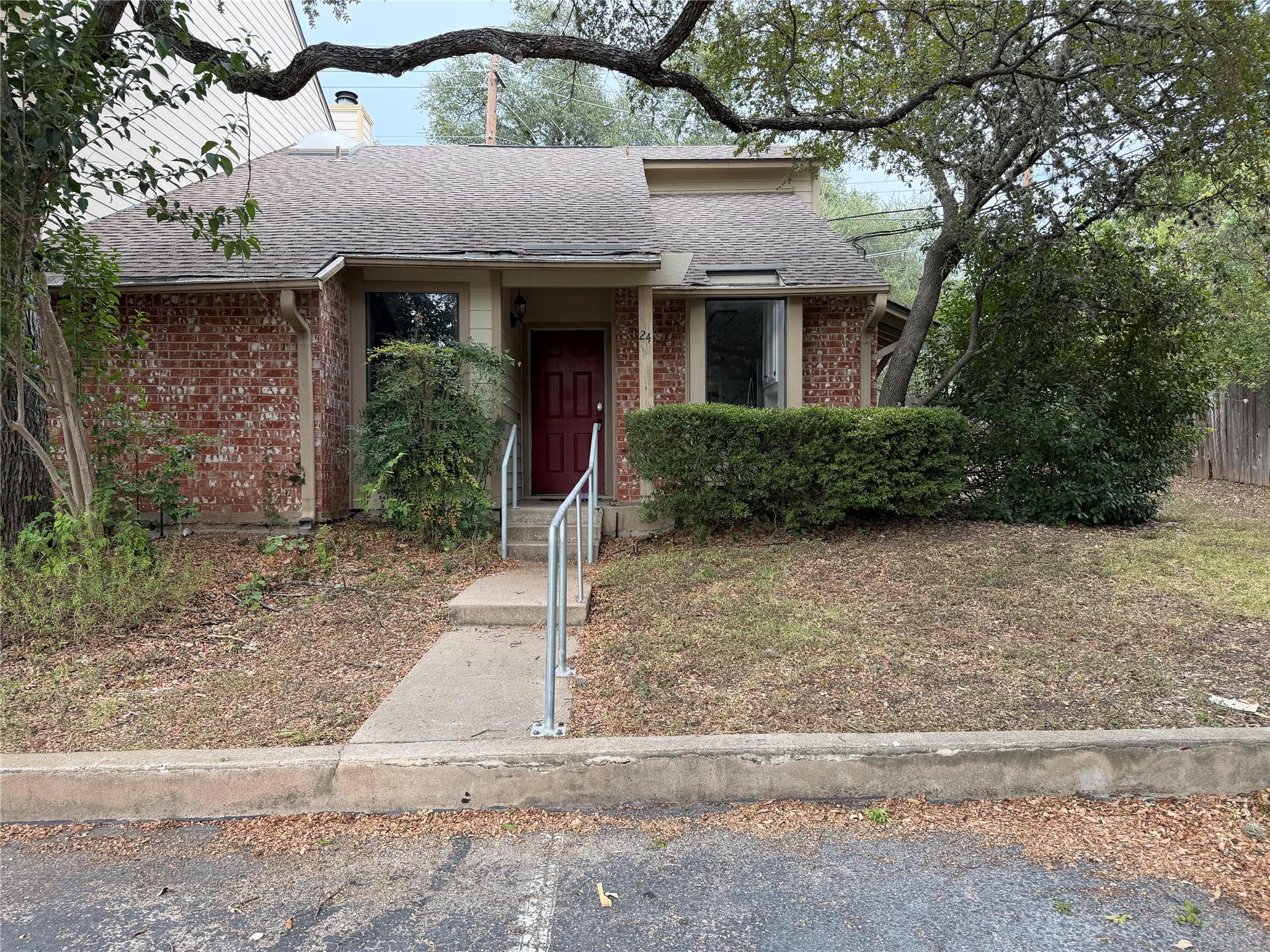 Mature trees frame a classic brick exterior featu