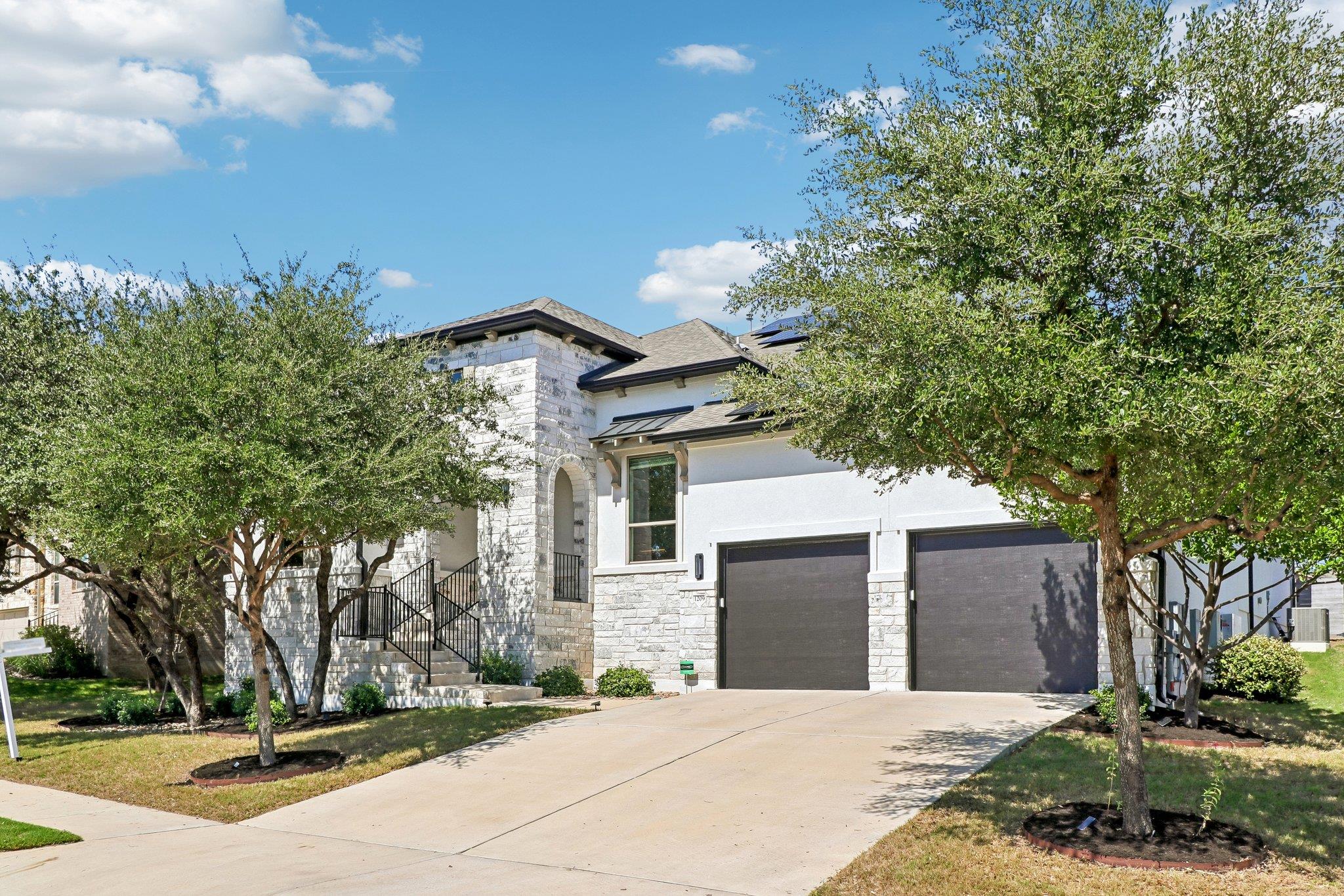 Limestone masonry and dark garage doors define th