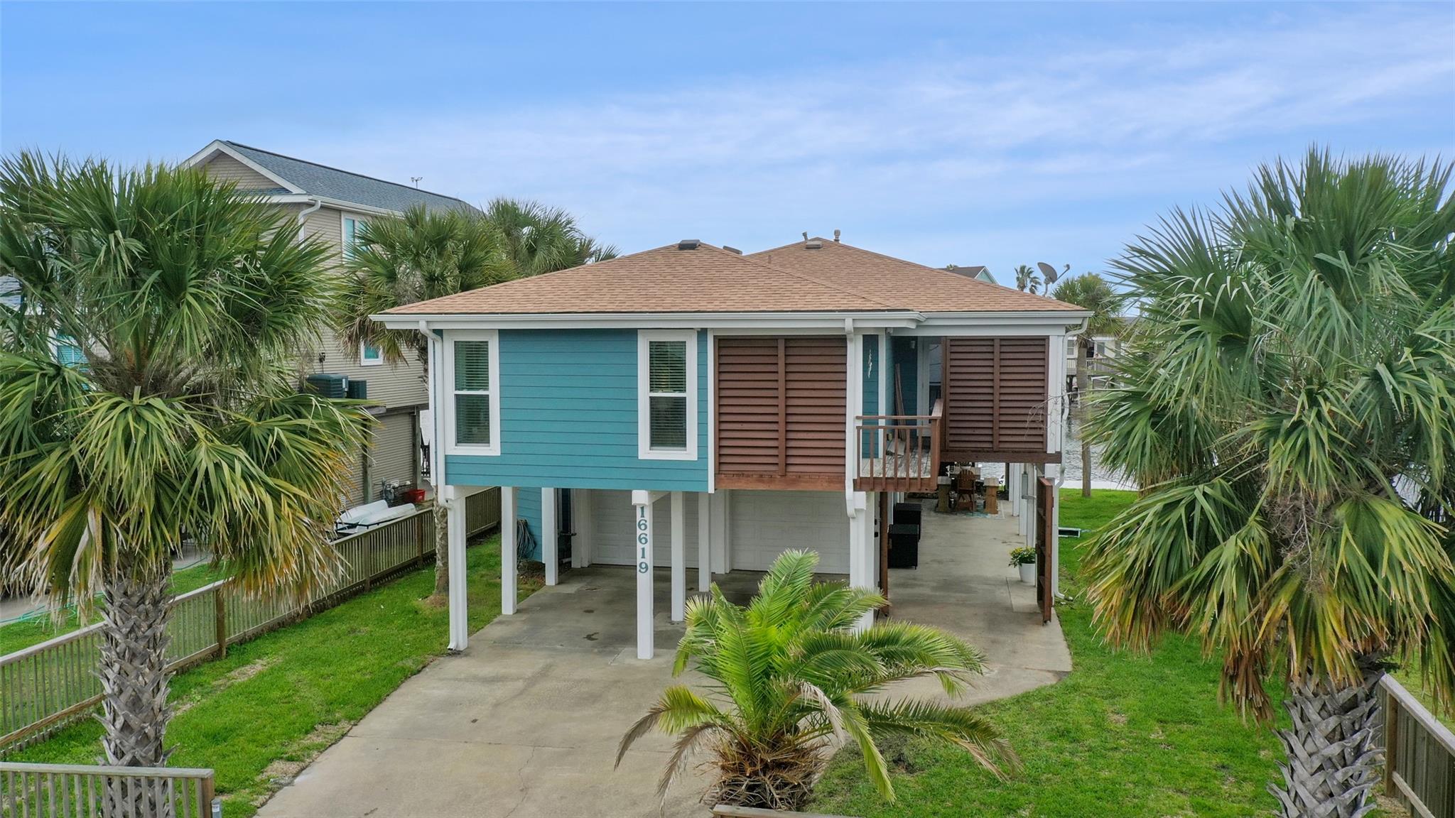 A coastal-style stilt home stands framed by palm 