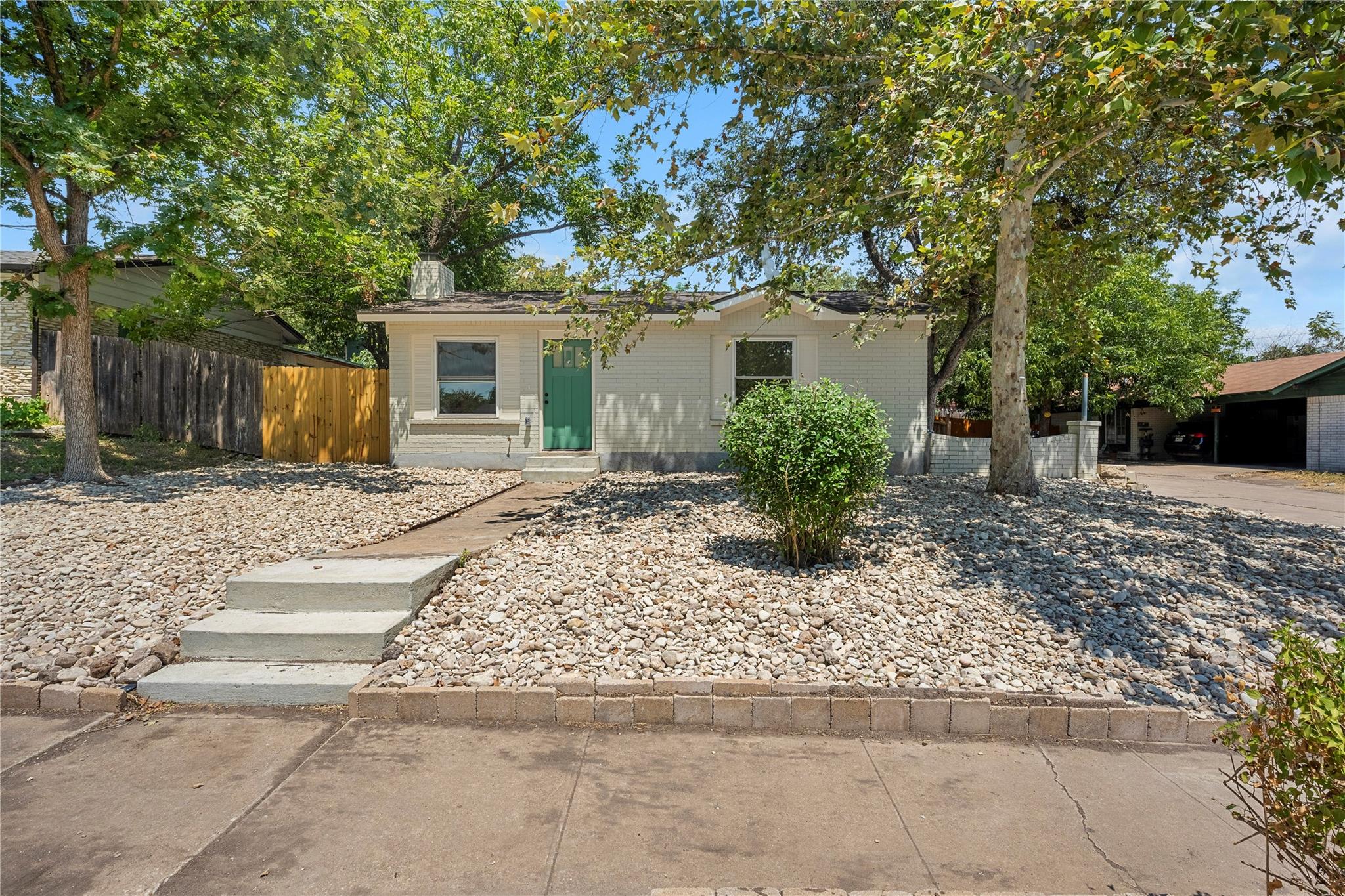 Mature trees shade the gravel front yard and conc
