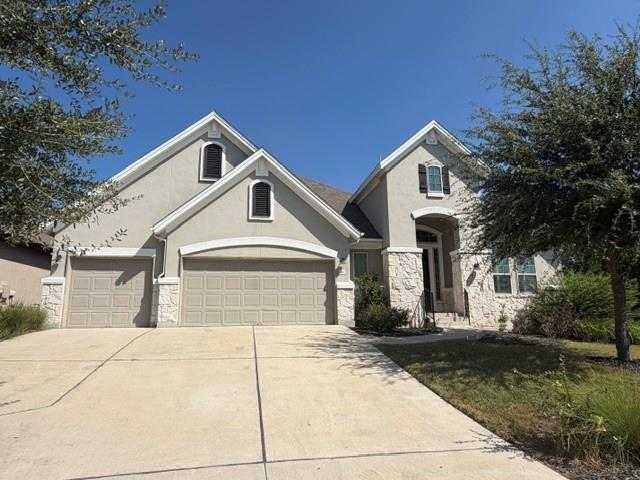 A spacious concrete driveway leads to this stone 