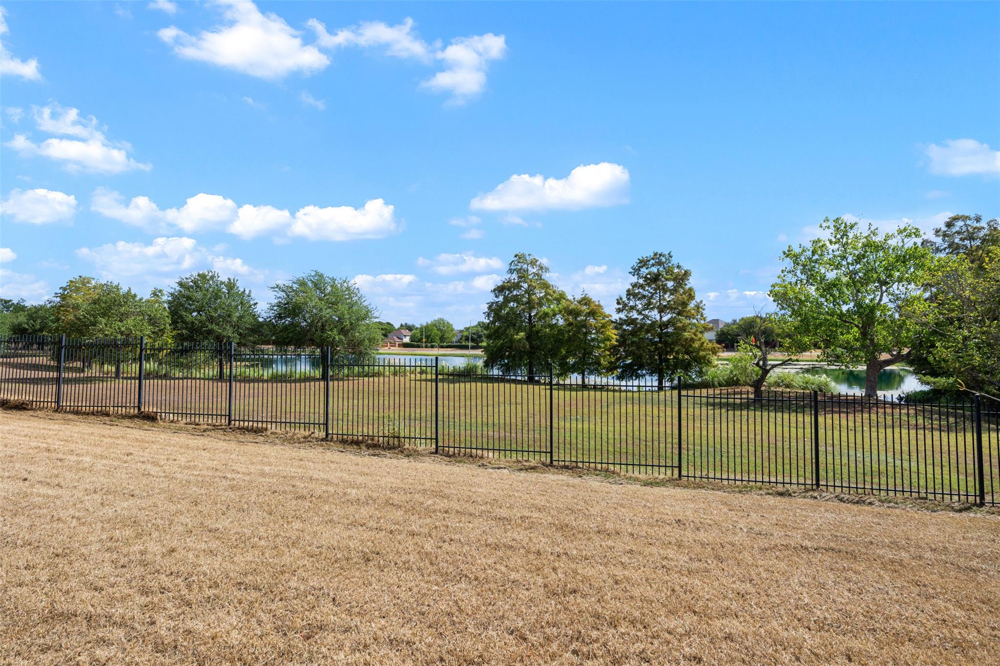 Metal fencing frames serene neighborhood pond vie