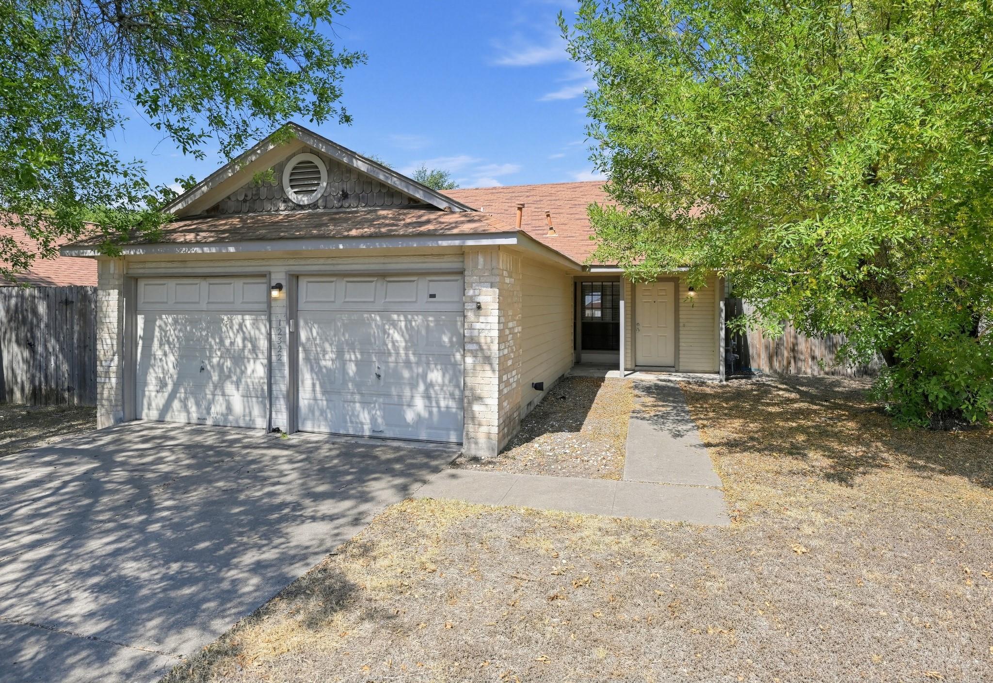 Mature trees shade the front yard and concrete wa