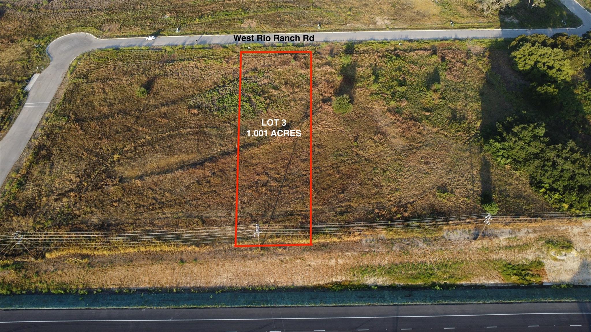 An expansive cleared lot borders paved roadways, 