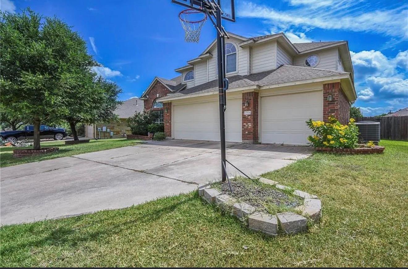 An expansive concrete driveway leads to a three-c