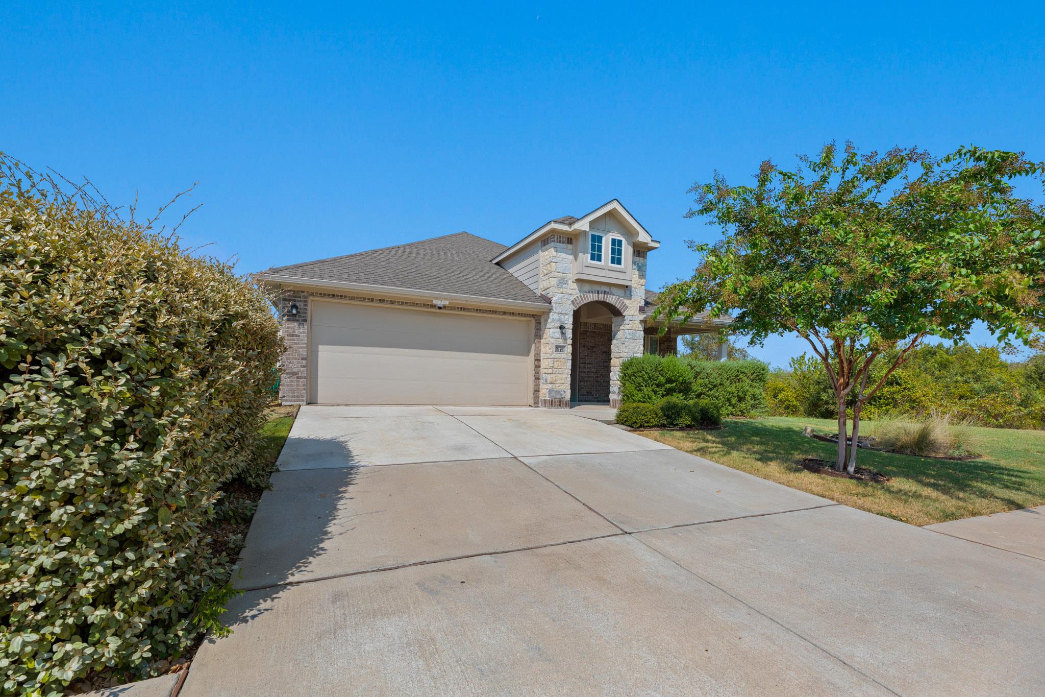 An arched stone entryway and wide driveway highli