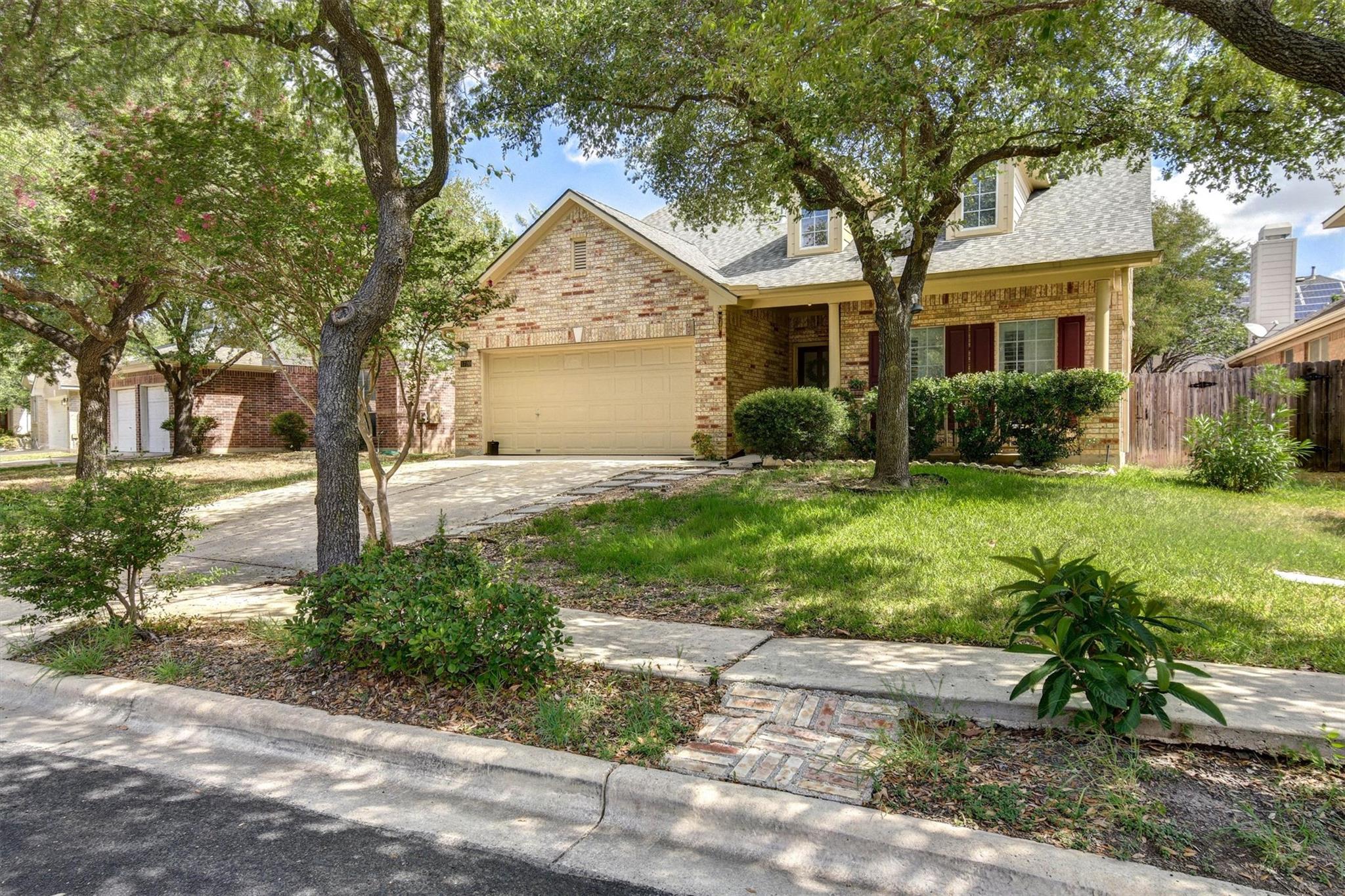 Mature trees frame this brick home featuring a tw