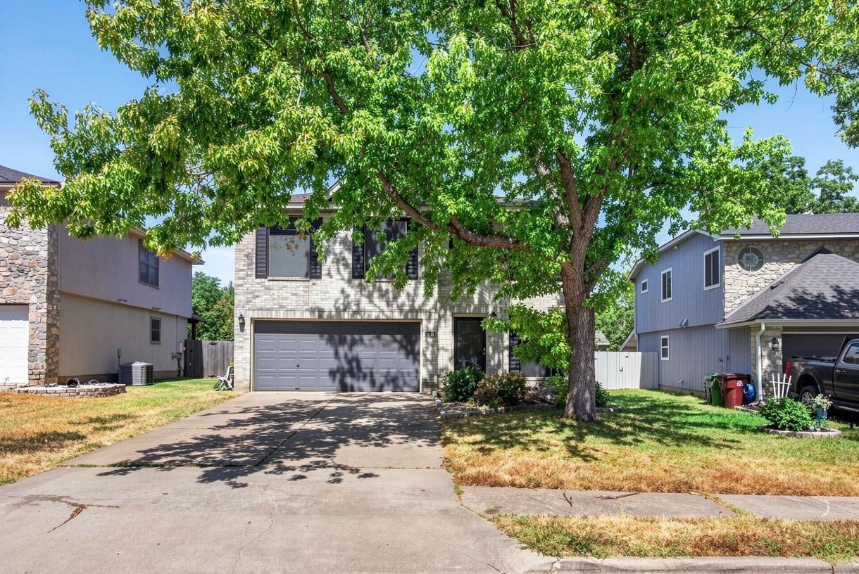 Mature trees shade a classic brick and siding ext
