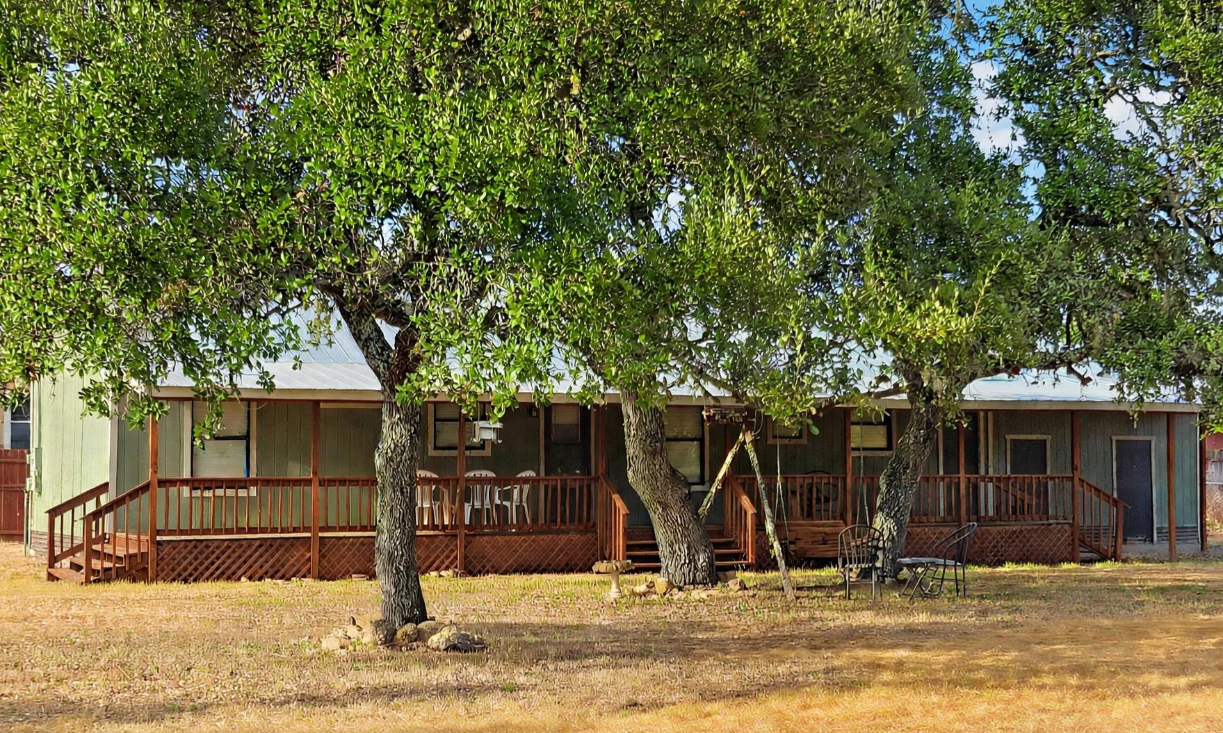 Mature shade trees frame a covered front porch sp