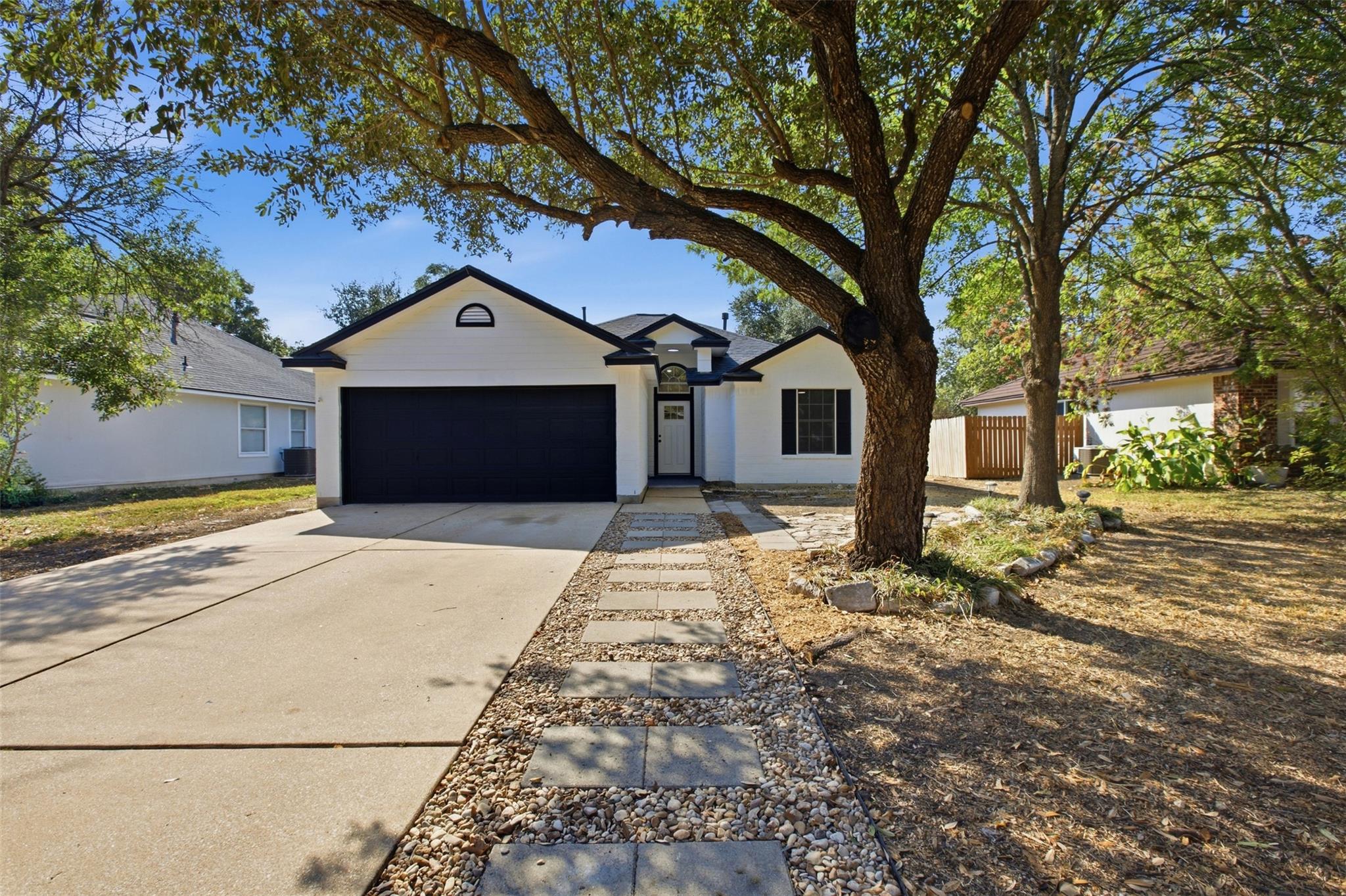 Mature trees shade a paved driveway and geometric