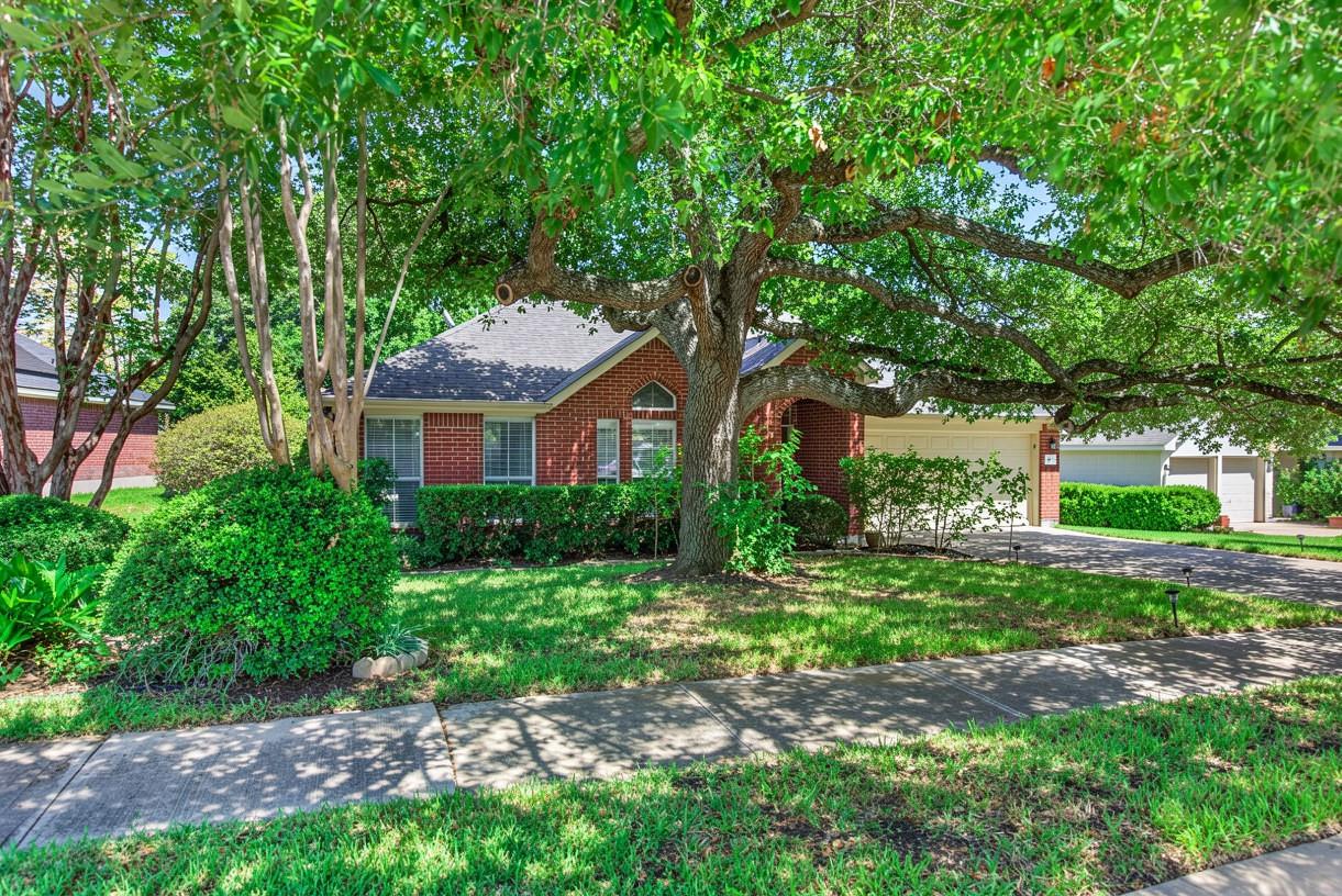 Mature shade trees and manicured lawns frame this