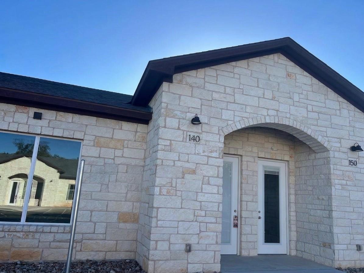 An arched stone entryway leads to glass-paneled d