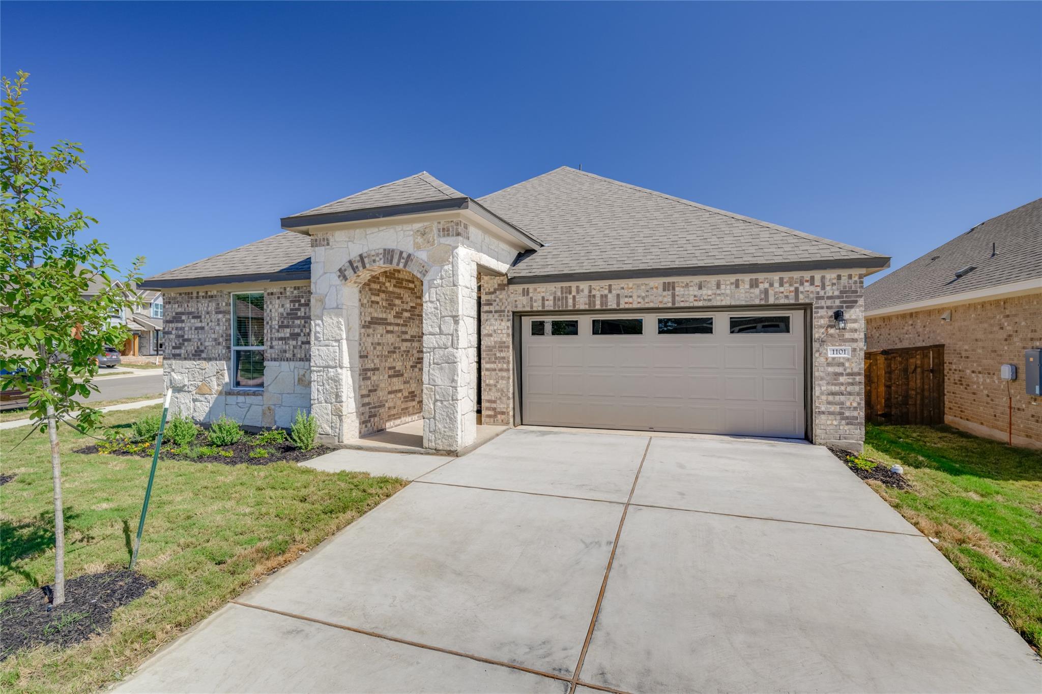 A stone-accented arched entryway and wide drivewa