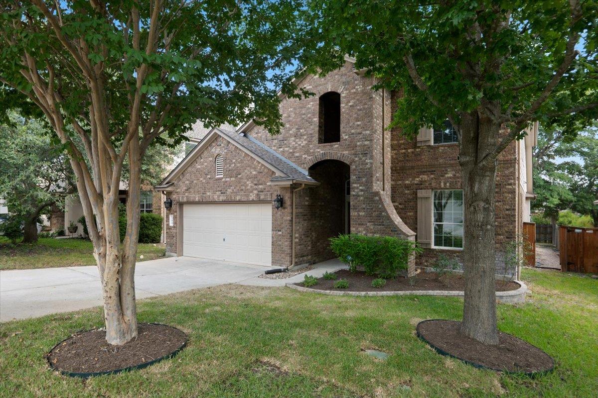 Towering trees shade a classic brick facade featu