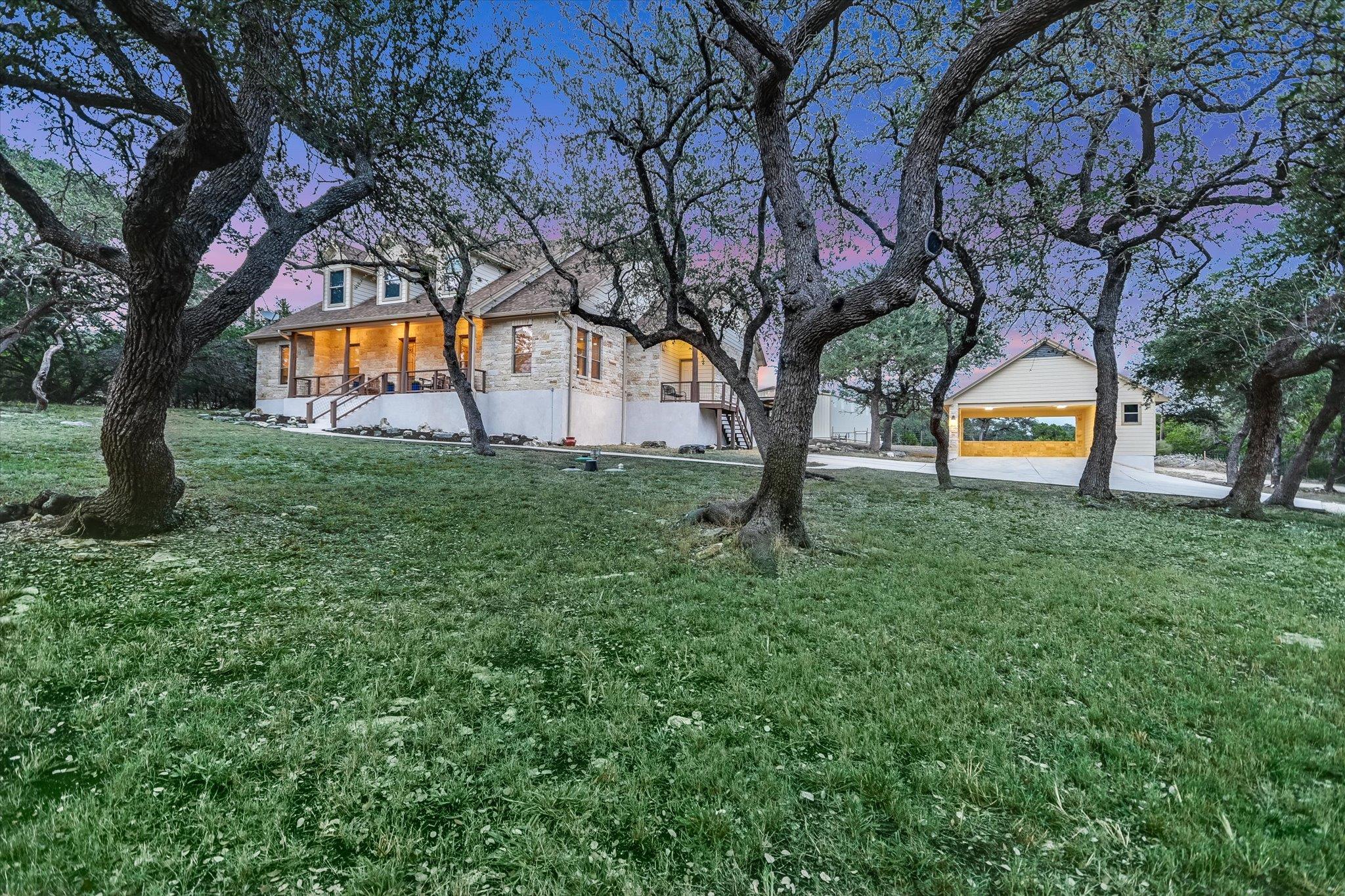 Mature oak trees frame a stone exterior sitting o