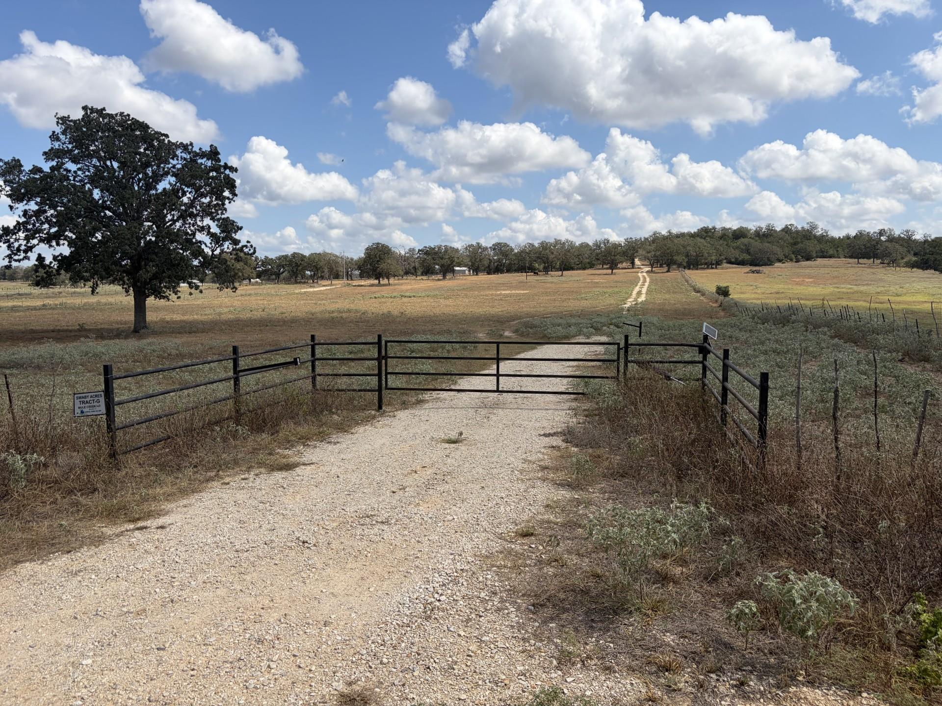 A gated entrance opens to a gravel path winding t