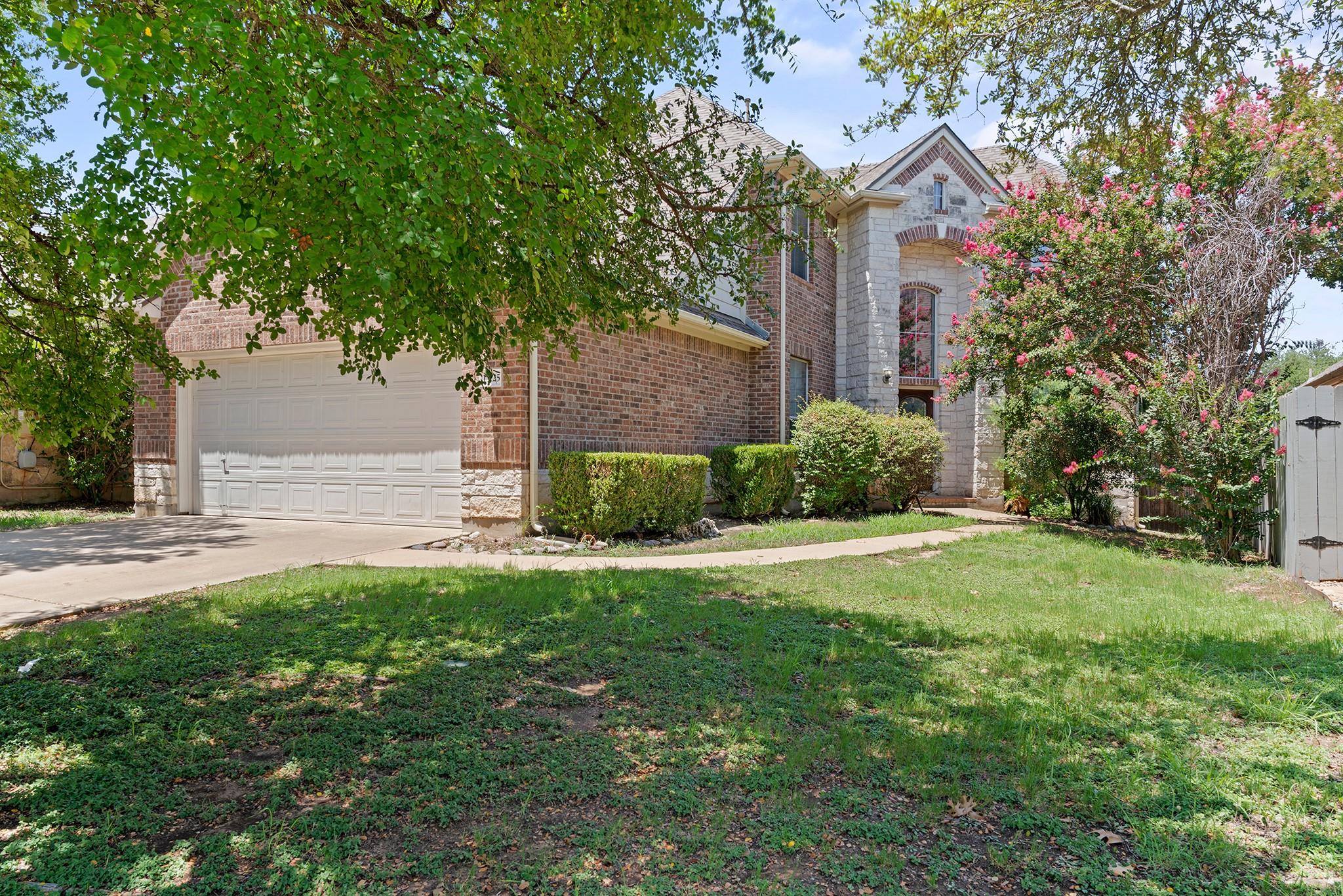 Mature trees shade the brick and stone facade of 